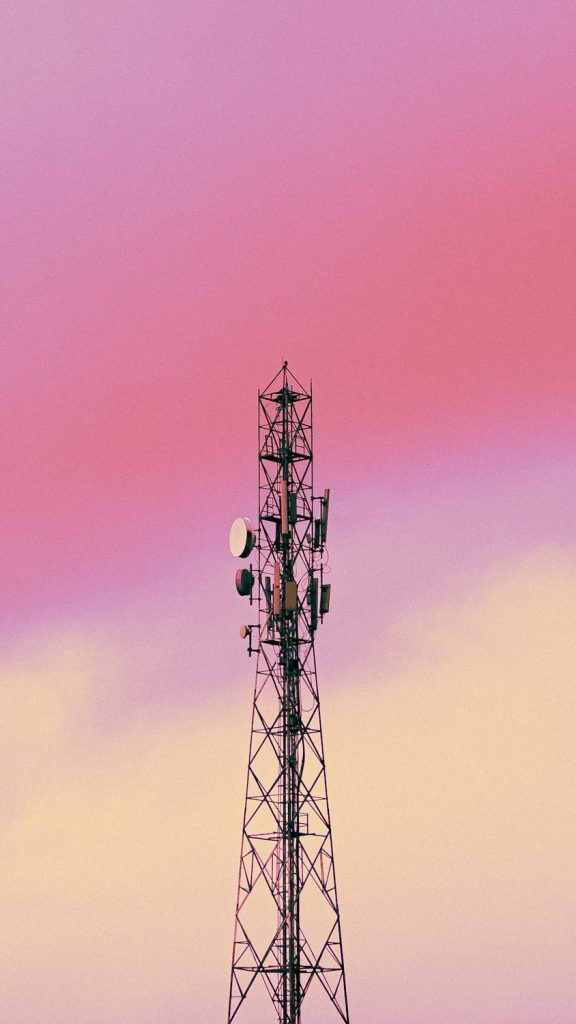 a cell phone tower with a pink sky in the background